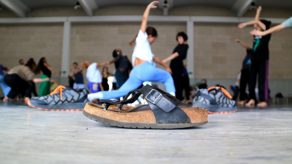 Primer pla d'unes sabates davant d'un grup de ballarins fan classe a Deltebre Dansa.