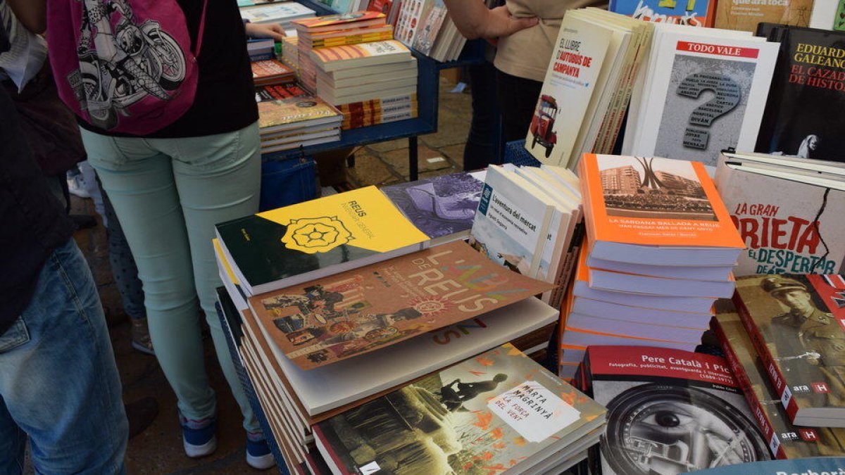 Rosas y libros inundan, un año más, la plaça del Mercadal de Reus. El punto más céntrico de la ciudad y sus alrededores se han llenado de paradas|puestos para ofrecer, a todo el mundo que lo quiera, la posibilidad de comprar el libro deseado y la rosa para|por la pareja, amigos o familiares.