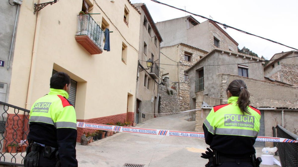 Dos agentes de los Mossos D'Esquadra delante del precinto que da acceso a la calle donde vivían los vecinos que se han peleado en Arbolí.