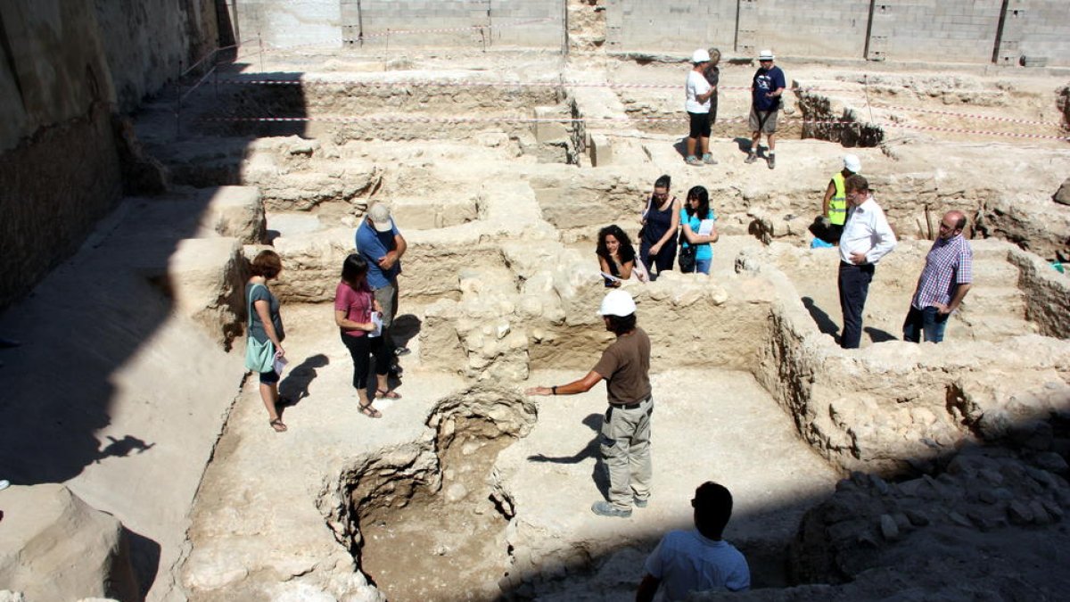 Zona on s'ha trobat una plaça del segle I mentre la visiten representants dels consistori, els directors de l'excavació i la premsa.