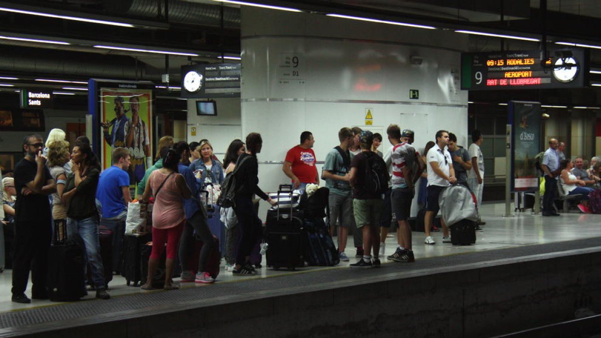 Usuaris esperant el tren a l'andana de l'estació de Sants