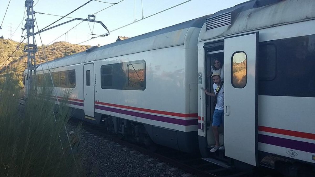 Usuarios de un tren parado entre Flix y Mora por|para una avería de electrificación a la línea esperan que les vengan a rescatar para poder continuar el viaje el 18 de julio del 2016. Plan|Plano general