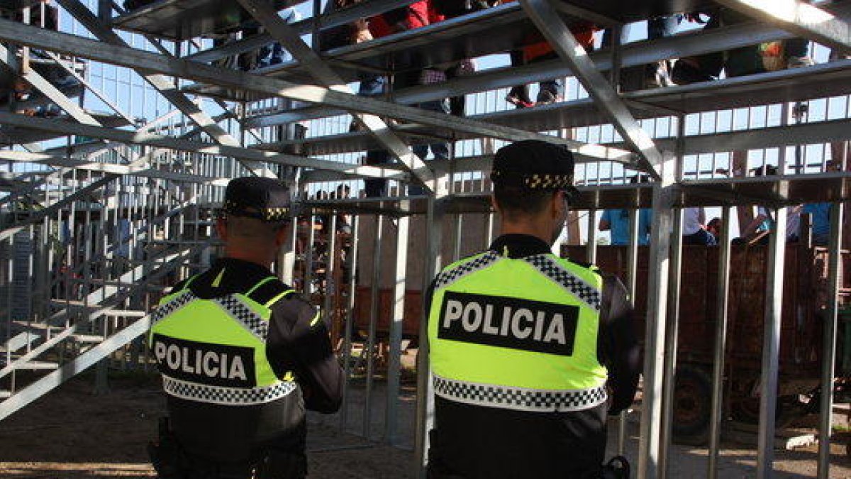 Dos agentes de la policía local de Alcanar, de espaldas, a la plaza.