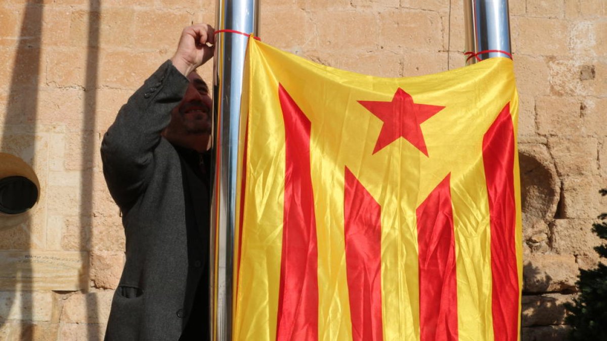 El portavoz de Alternativa Baix Gaià, Lluís Suñé, cuelga una estelada entre dos palos del Ayuntamiento de Torredembarra.