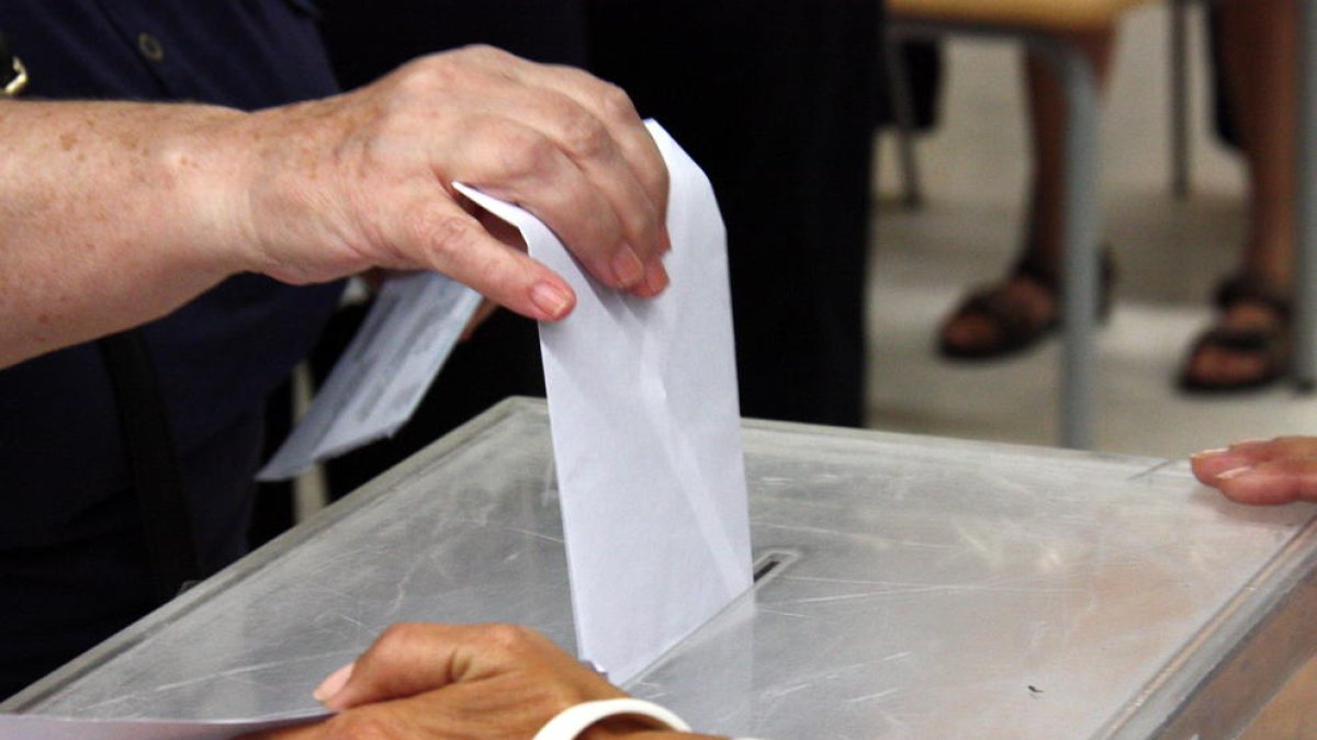 Detall d'un votant introduïnt la papereta en una urna