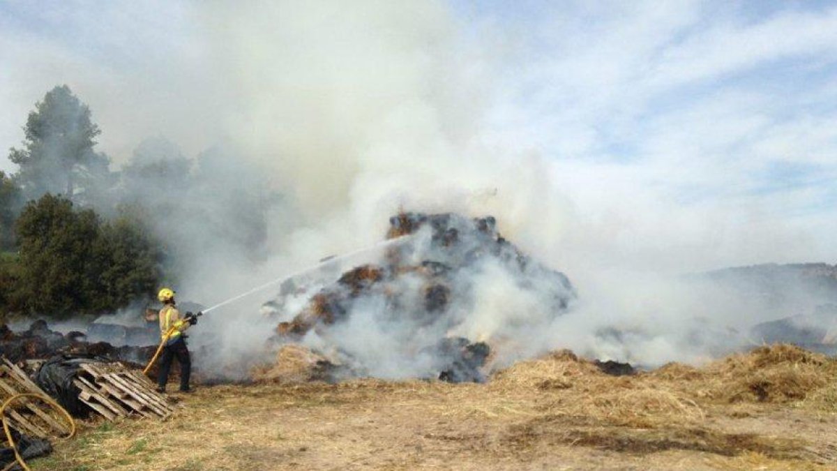 Un bombero remojando el pajar.