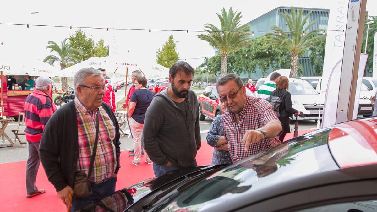 Visitants a la fira en un estand d'automòbils.