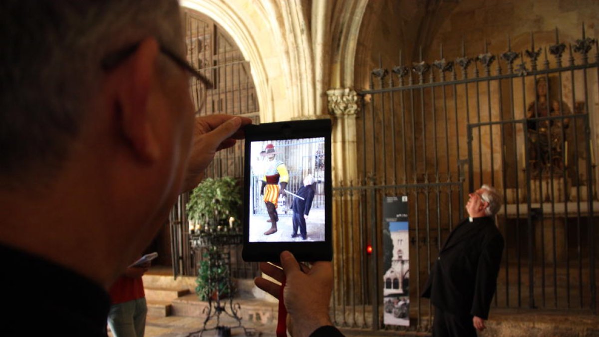 L'arquebisbe de Tarragona, Jaume Pujol, amb l'iPad a la mà, enfocant al degà-president del Capítol de la Catedral de Tarragona, Joaquim Fortuny, i al costat apareix, en realitat augmentada, un cavaller gegantí de l'època, Francisco Plaza