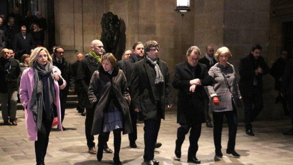 El expresidente Artur Mas mira el reloj al lado del presidente de la Generalitat, Carles Puigdemont, y la presidenta del Parlamento, Carme Forcadell; y Joana Ortega e Irene Rigau, a los cocheros de la Generalitat, el 6 de febrero de 2016.