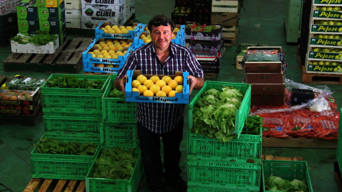 El president de la Cooperativa de l'Aldea, Miguel Carles, entre caixes de verdures i fruites al magatzem de l'agrobotiga de l'entitat