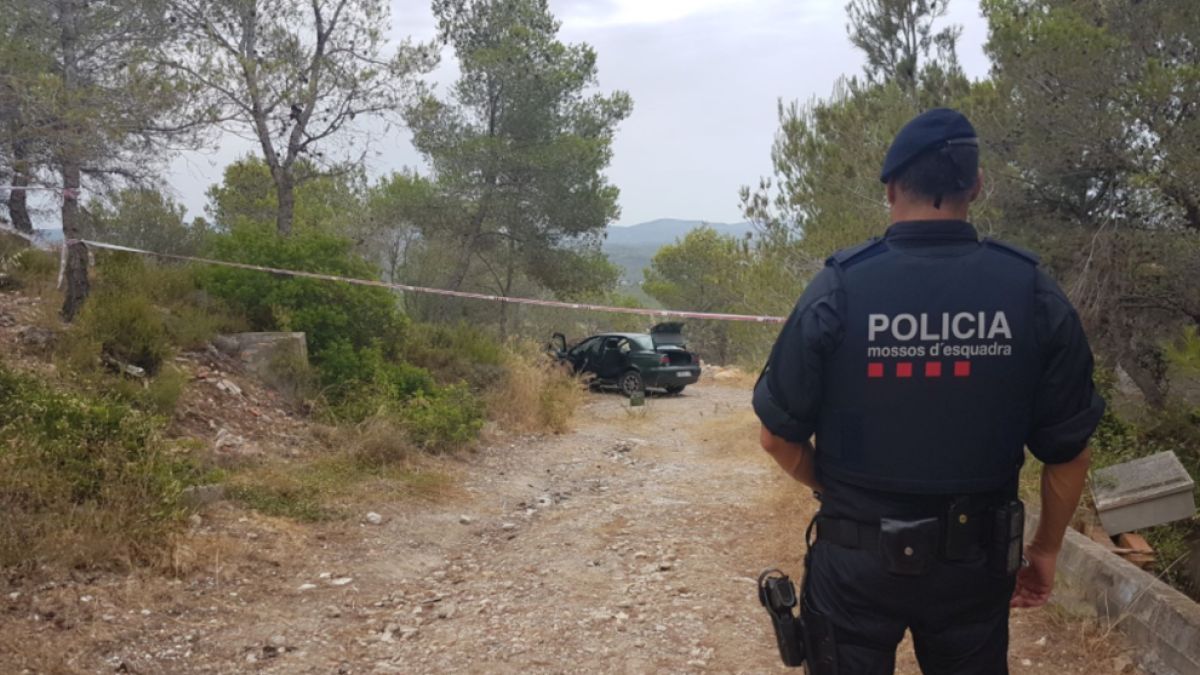 Un agent de Mossos d'Esquadra, amb el cotxe del detingut al fons.