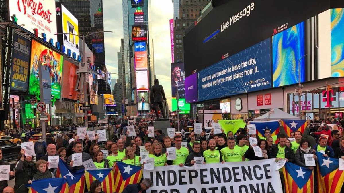 Fotografia de diversos corredors de la Marató de Nova York a Times Square amb estelades i pancartes demanant l'alliberament dels presos polítics.