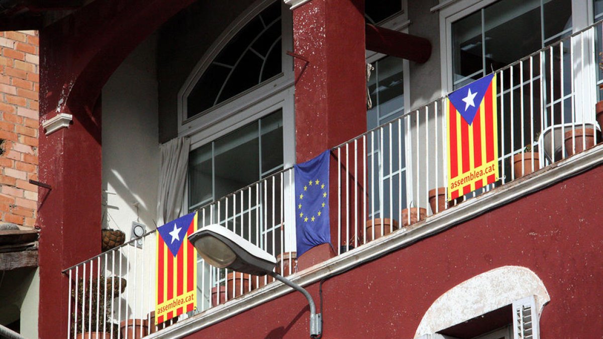 Banderes estelades en un balcó, al costat d'una bandera europea.