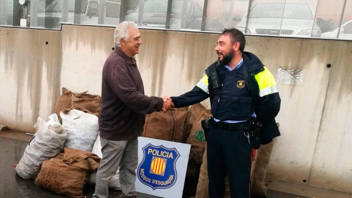 Un agente de los Mossos y el campesino propietario de las algarrobas robadas en la Canonja en el momento que se efectuó el retorno del fruto.