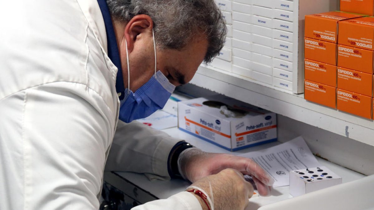 Un farmacèutic analitzant una mostra d'un test d'antígens.