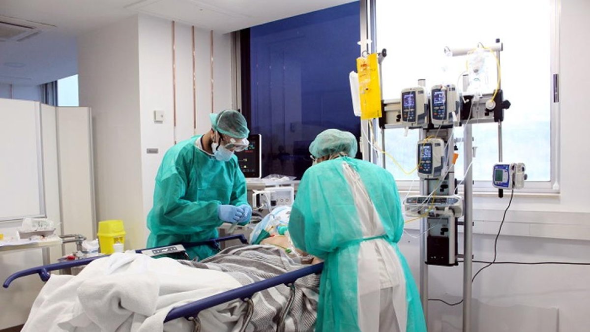 Imatge de dos professionals mèdics atenent un pacient a l'UCI.