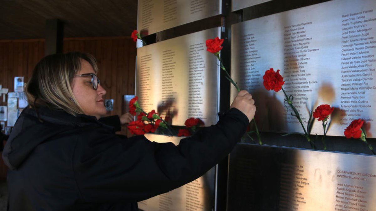 Una dona col·loca clavells al Memorial de les Camposines de la Fatarella.