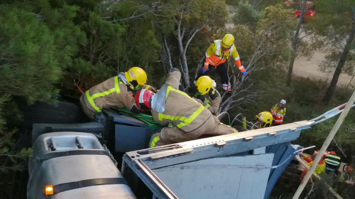 Los bomberos intentando sacar al camionero de la cabina.