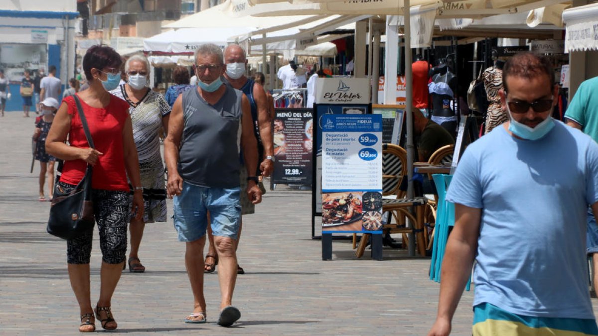 Persones passejant amb mascaretes per la zona marítima de Calafell Platja, el punt més turístic del municipi.