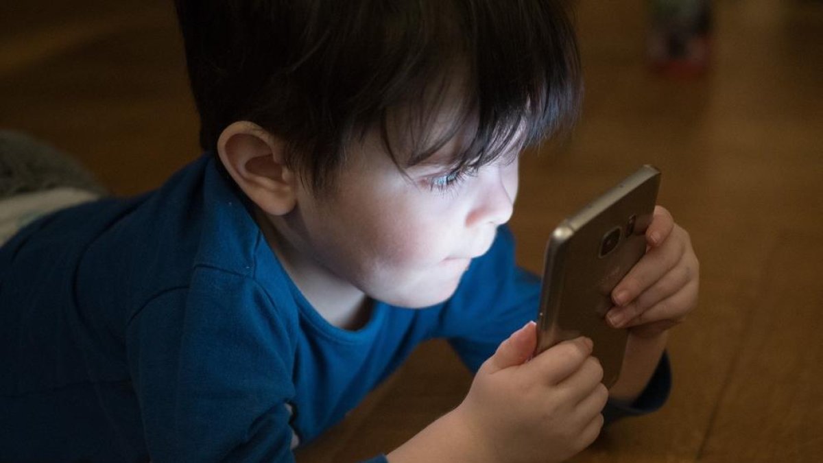 Un nen petit fixat amb una pantalla de mòbil.