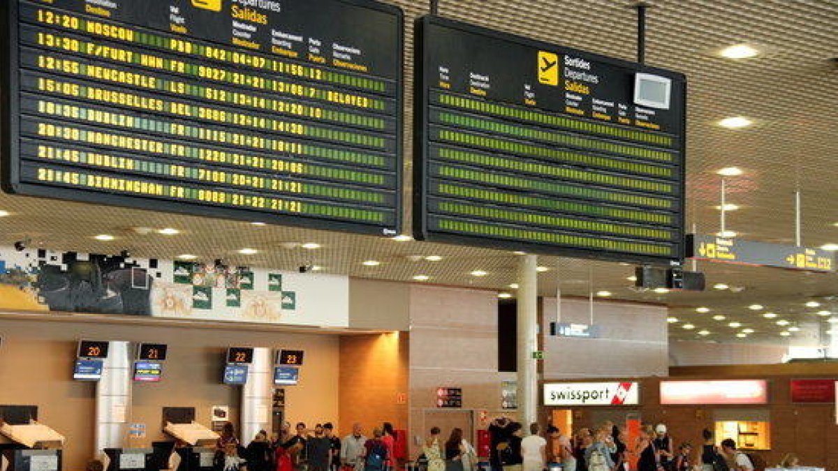 Pantalla indicando un retraso en un vuelo de Ryanair a Frankfurt y colas de fondo en el Aeropuerto de Reus.