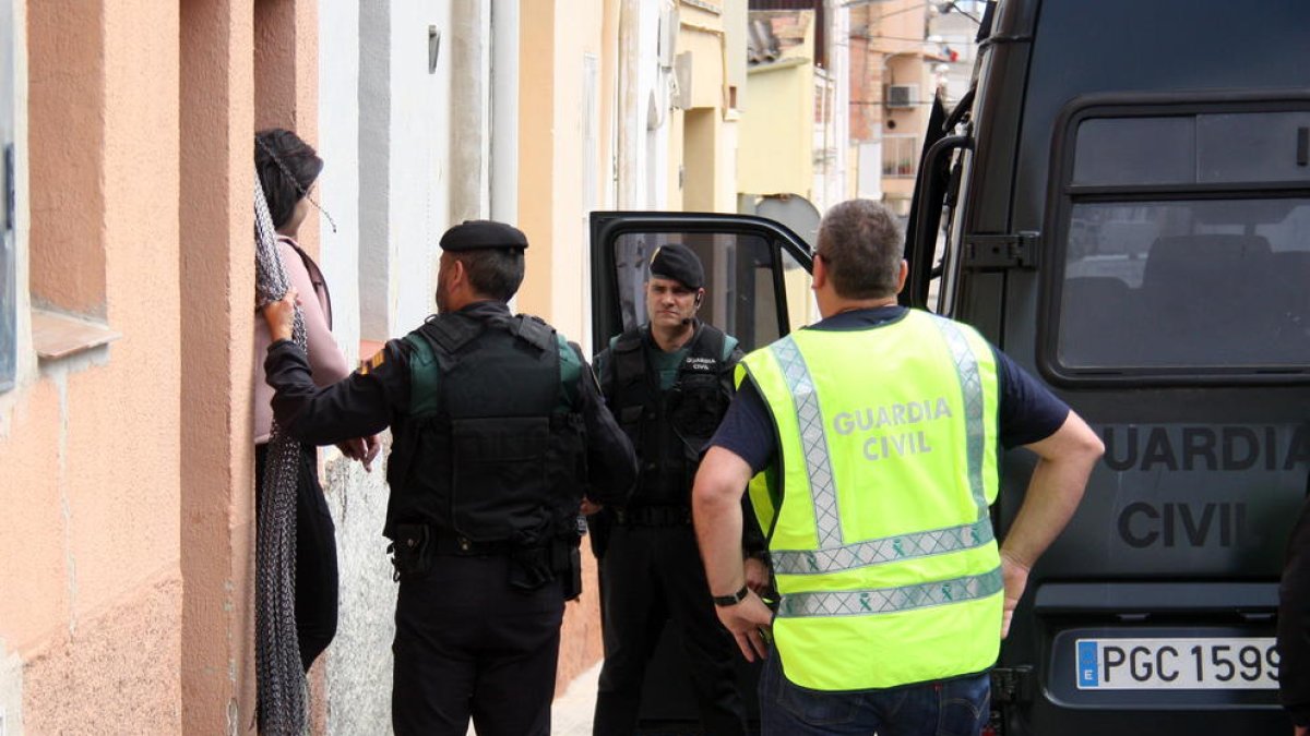 Una mujer detenida saliente de una de las viviendas, al lado de agentes de la Guardia Civil, en Amposta, durante una operación contra el tráfico de drogas, este 12 de mayo de 2016