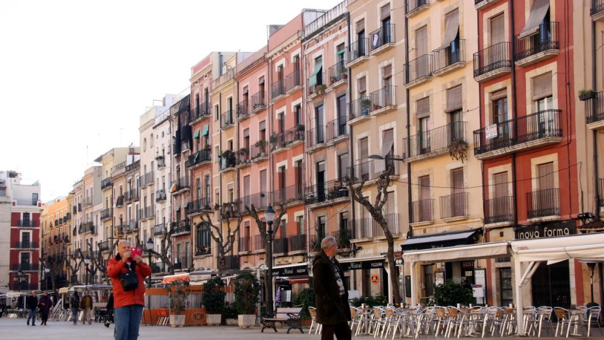 Un par de turistas paseando y haciendo fotos con el móvil en la plaça de la Font de Tarragona.