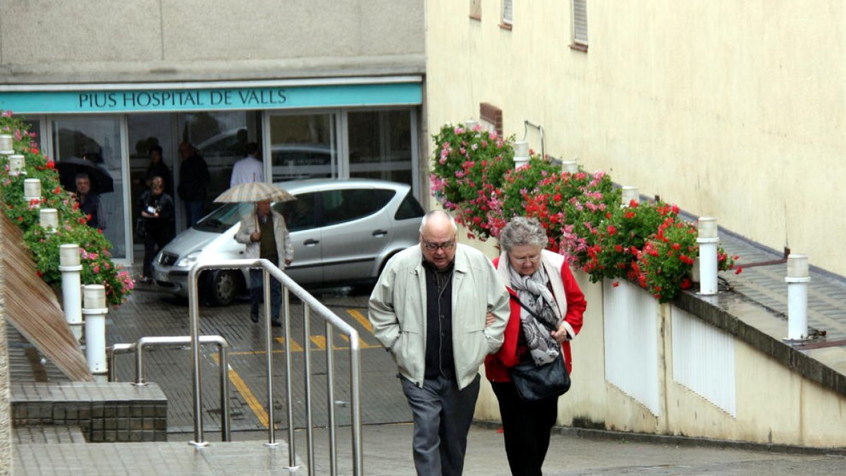 Una parella d'avis, pujant el pronunciat pendent del Pius Hospital de Valls, el 28 d'abril de 2016