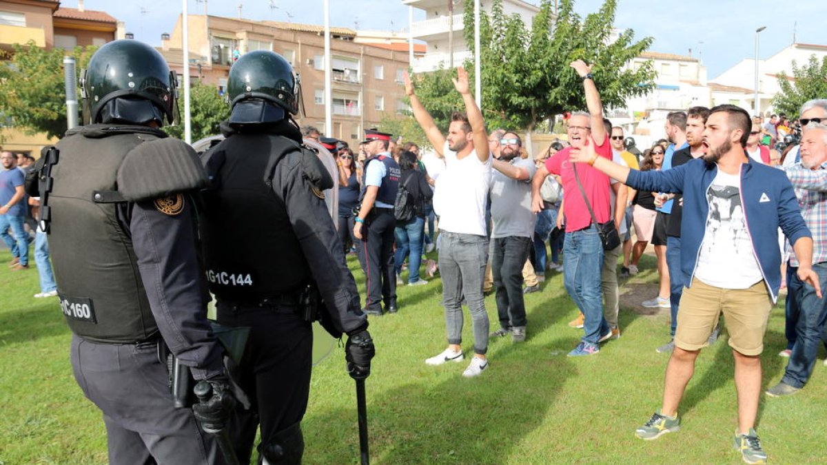 Dos agents antiavalot de la Guàrdia Civil davant de diversos ciutadans amb els braços enlaire després d'entrar al Pavelló Firal de Móra la Nova i endur-se una urna.