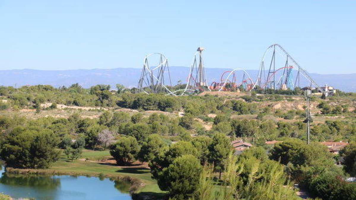 Terrenos del Centro Recreativo y Turístico (CRT) de Vila-seca y Salou, con un lago y campo de golf de PortAventura (Lumine) en primer término, y las atracciones al fondo.