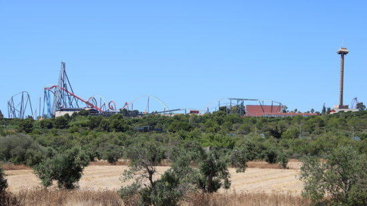 Campos agrícolas donde está previsto el Centro Recreativo y Turístico (CRT) de Vila-seca y Salou y, en el fondo, montañas rusas del parque de atracciones PortAventura.