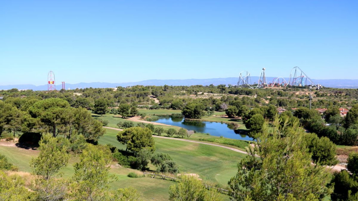 Panoràmica dels terrenys on s'ha projectat el Centre Recreatiu i Turístic (CRT) de Vila-seca i Salou, amb el parc temàtic PortAventura, de fons, en una imatge del juliol del 2017