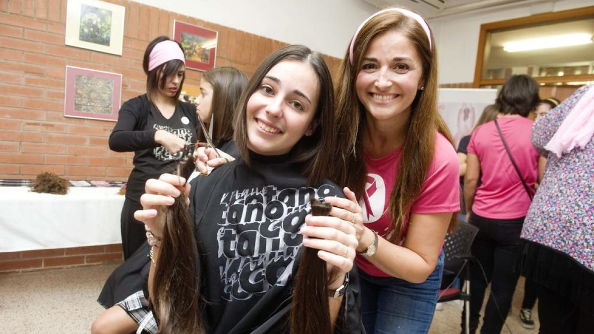 Una alumna sostenint la cua de cabell que s'ha tallat per donar-la a la fundació Mechones solidarios.