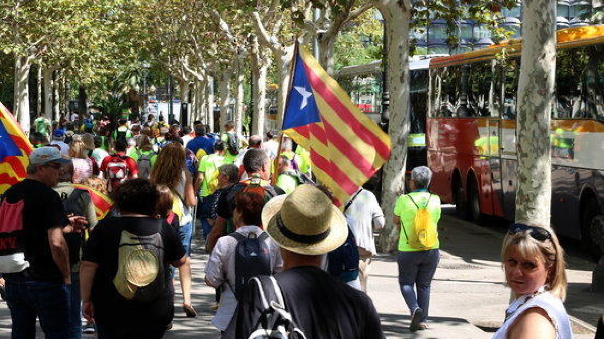 Plano general subido de decenas de participantes a la manifestación de l'ANC y Òmnium andando|caminando `por la avenida Diagonal después de bajar de los autobuses.