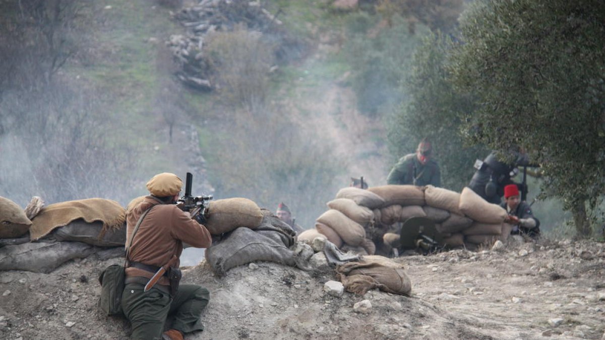 Plano abierto de la recreación del último combate de la Batalla del Ebro, con una trinchera republicana y soldados nacionales que avanzan.