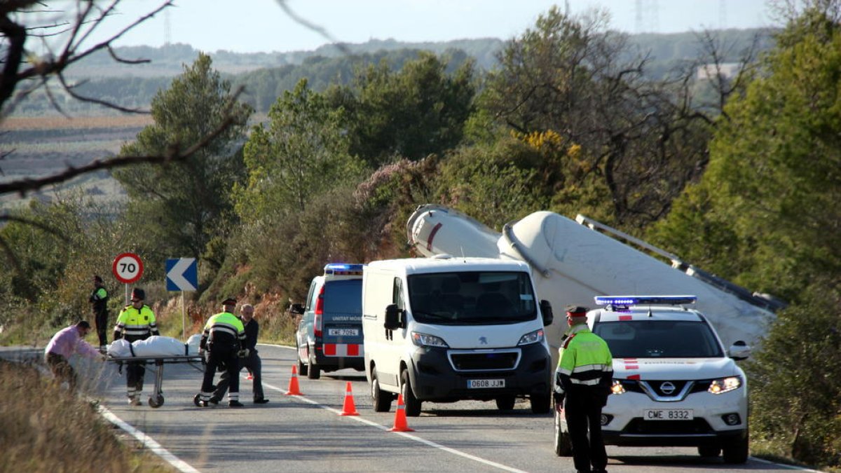 Imatge del camió cisterna accidentat mentre els forenses i els mossos retiren el cos de la víctima. Pla general