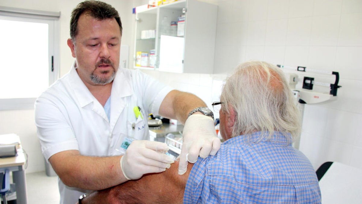 Un infermer posant la vacuna de la grip a un pacient.