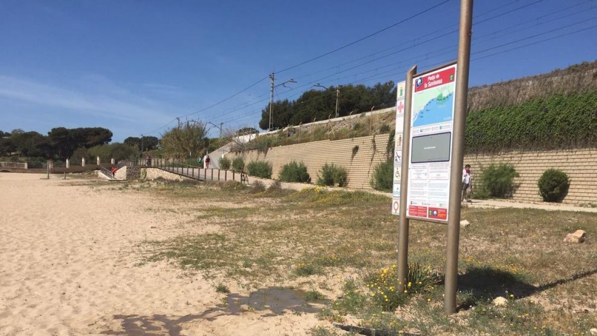 El agua escapa bajo el cartel de playa azul.