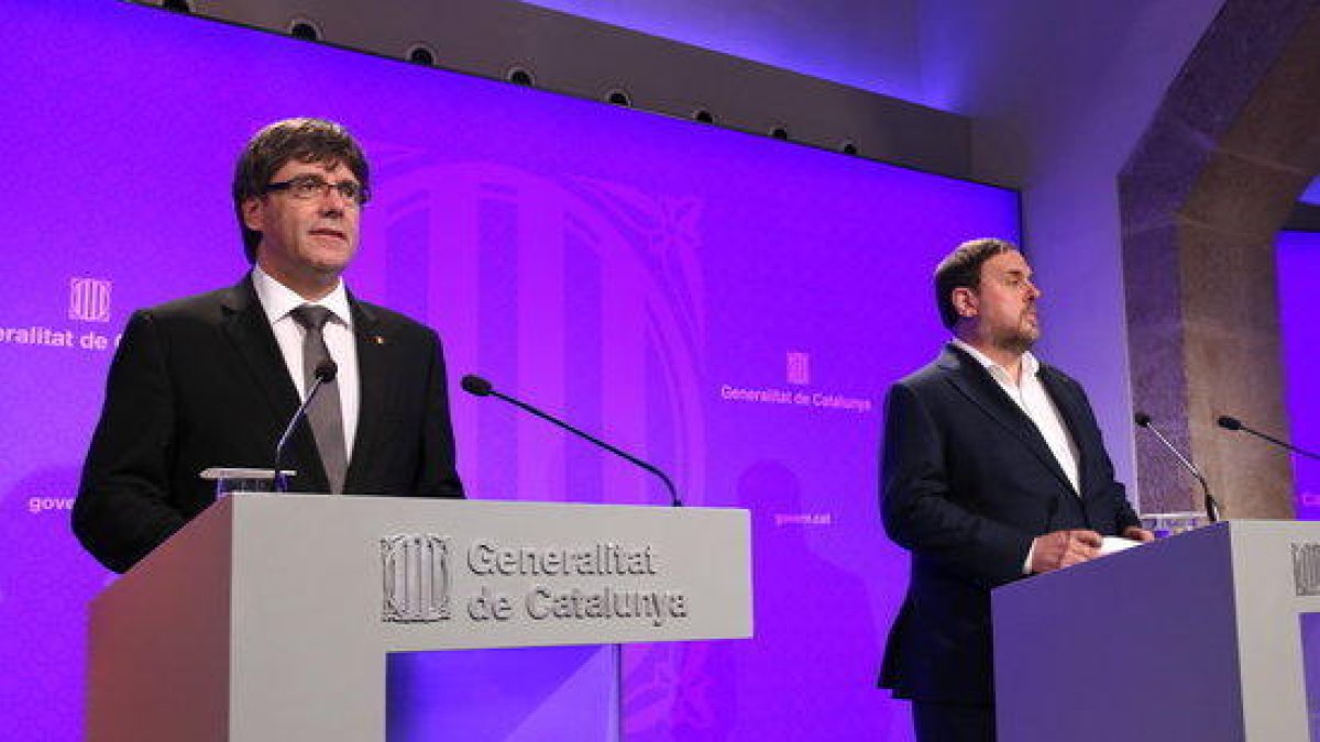 El president del Govern, Carles Puigdemont, i el vicepresident, Oriol Junqueras, compareixen a la sala de premsa del Palau de la Generalitat per explicar els canvis a l'executiu.