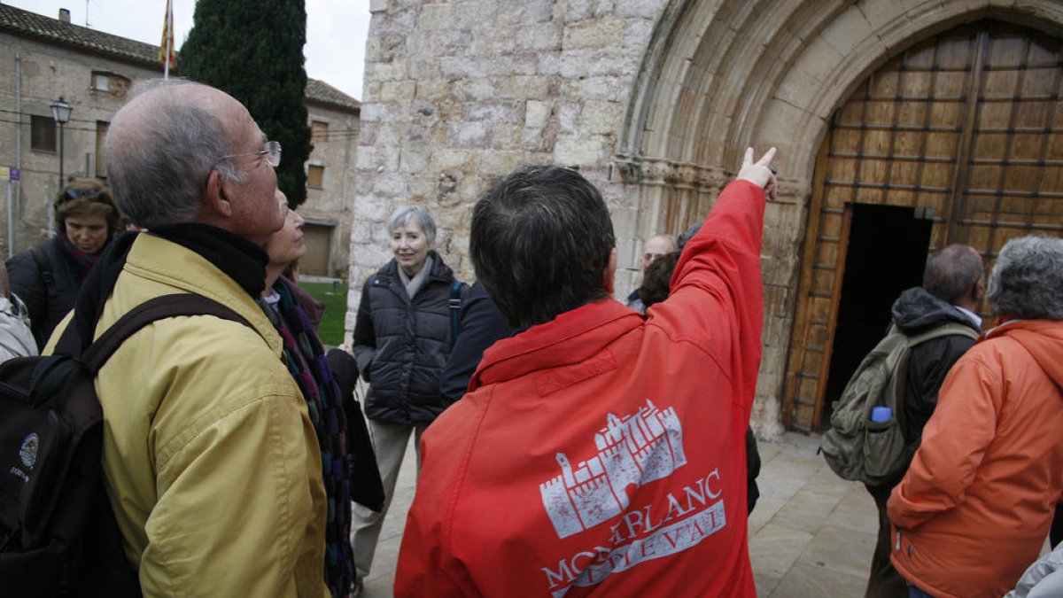 Pla mig d'un guia donant explicacions a un grup de turistes de visita al patrimoni medieval de Montblanc
