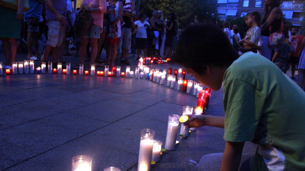 Imagen de archivo de un niño poniendo velas por los asesinatos machistas de dos mujeres y dos menores en Castelldefels en el 2015.