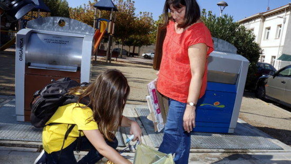 Imatge d'arxiu d'una educadora comprovant el reciclatge d'una veïna.