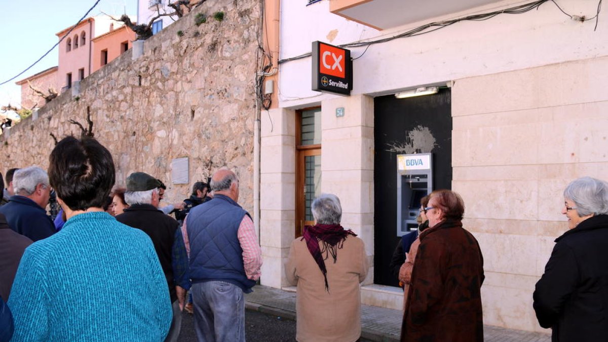 Alguns veïns de Rasquera davant del caixer automàtic del BBVA que no funciona on han llençat un ou. Imatge del 14 de febrer de 20'17 (horitzontal)