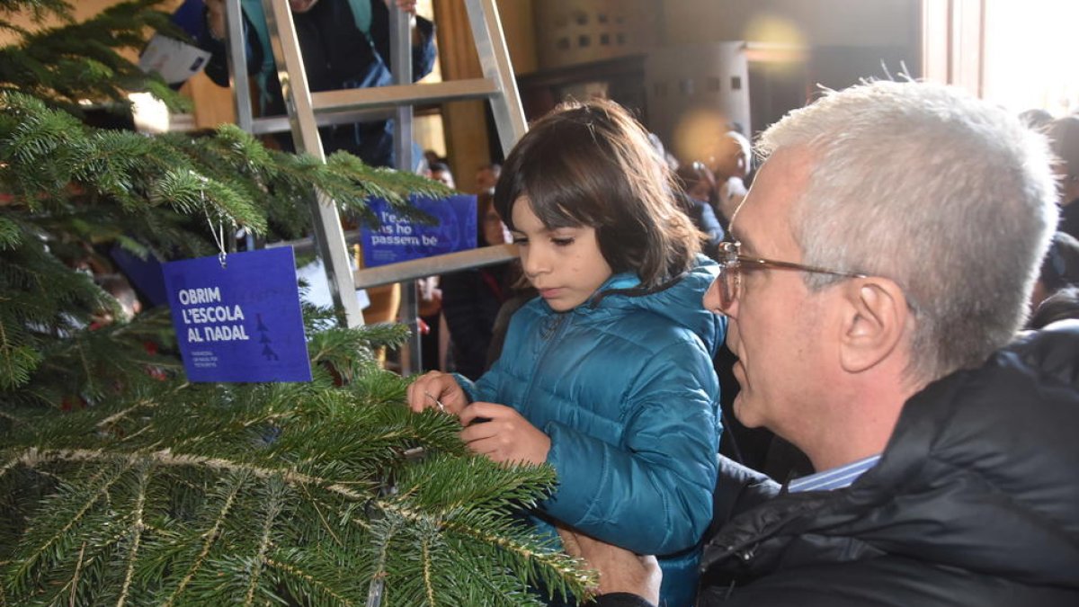 Josep Fèlix Ballesteros ayudando a colocar el mensaje a un niño.