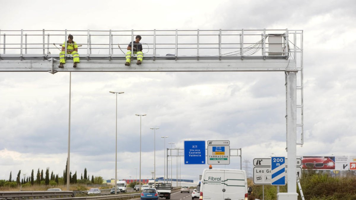 Dos operarios instalando el nuevo radar por tramo que ha entrado en funcionamiento este año en Tarragona.