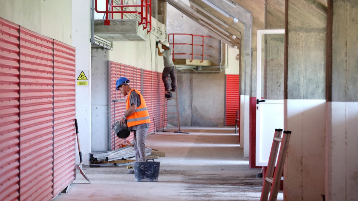 Dos trabajadores, en la zona de Tribuna, realizando los trabajos previos al acabado de la zona.