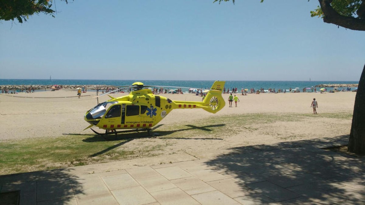 Pla obert de la platja de l'Horta de Santa Maria de Cambrils amb l'helicòpter a la sorra en primer pla. Imatge del 17 de juny de 2017