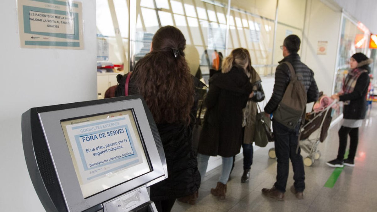 Diversos usuaris en el servei del punt d'informació al costat de la màquina fora de servei, ahir.