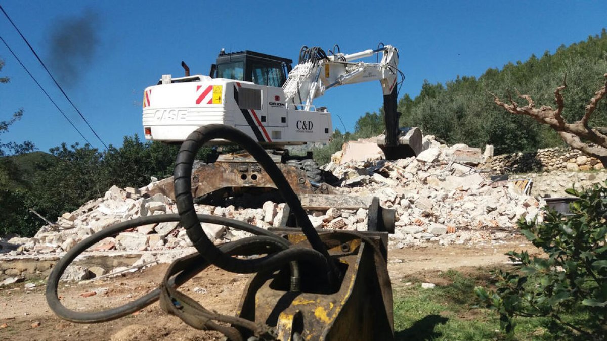 La máquina excavadora sobre los escombros de la casa destruida del matrimonio de Alfara de Carles. Imagen del 20 de marzo de 2017 (horizontal)