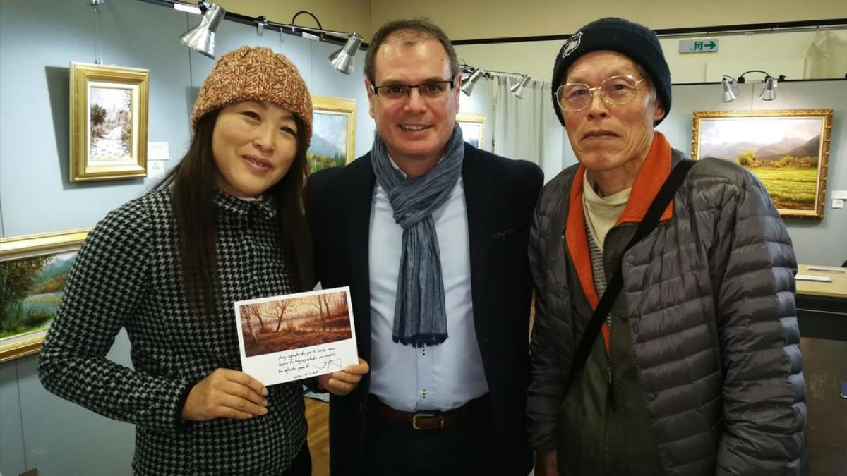 Dos admiradors japonesos mostrant una dedicatòria de Jordi Isern, al centre.